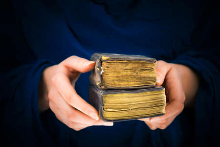 Woman's hands holding two old books in a blue tones backgroundの写真素材
