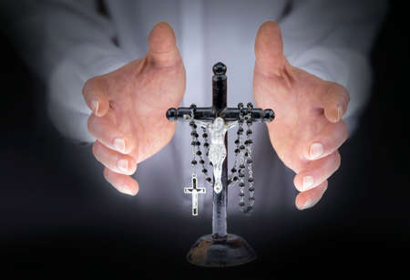 Close view of man's hands with crucifix and a black rosary