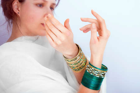 Young female in white cloth with  bracelets on her hands