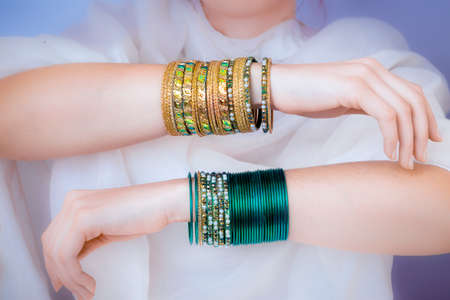 Girl hands with golden bracelets on a white clothの写真素材