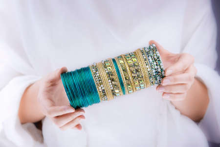Girl hands with golden bracelets on a white cloth