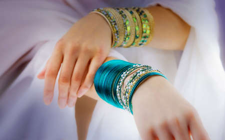 Girl hands with golden bracelets on a white clothの写真素材