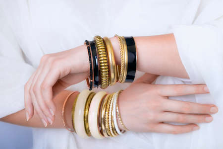 Girl hands with golden bracelets on a white clothの写真素材