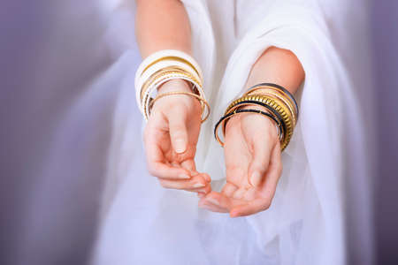 Girl hands with golden bracelets on a white clothの写真素材