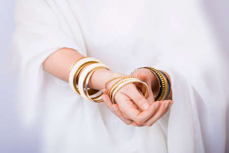 Girl hands with golden bracelets on a white clothの写真素材