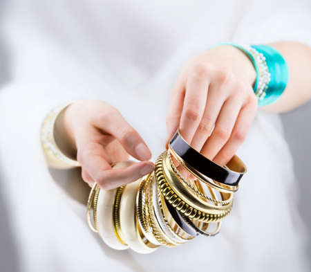 Girl hands with golden bracelets on a white clothの写真素材