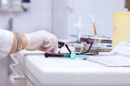 Eyeglasses on a dentist's table and dentist hand with a mirror in a clinicの写真素材