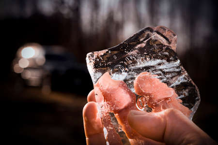 Men's hand with a piece of transparent ice in a black background