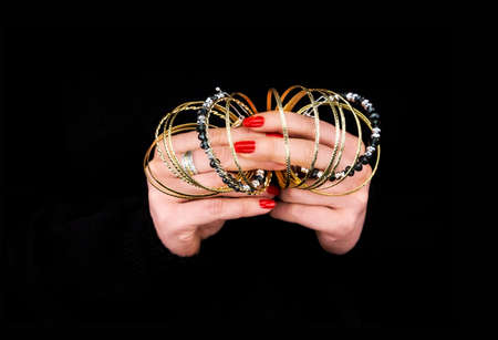 Woman's hands with golden bracelets in a black background
