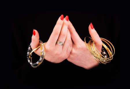 Woman's hands with golden bracelets in a black backgroundの写真素材