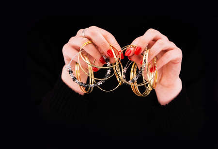 Woman's hands with golden bracelets in a black backgroundの写真素材