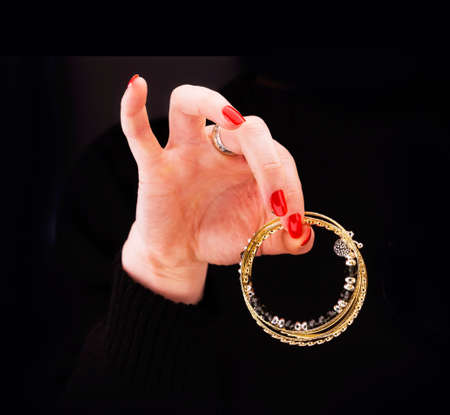 Woman's hand with golden bracelets in a black backgroundの写真素材