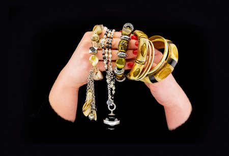 Woman's hands with various bracelets in a black backgroundの写真素材