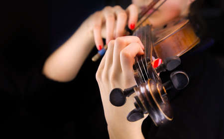 Woman's hands playing the violin in a black backgroundの写真素材