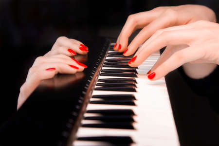 Four woman's hands on synthesizer keyboard in a black backgroundの写真素材