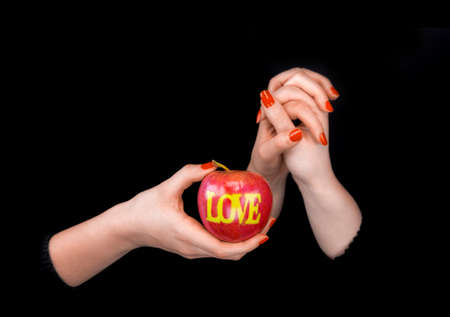 Two women holding their hands and showing an apple with word love in black backgroundの写真素材