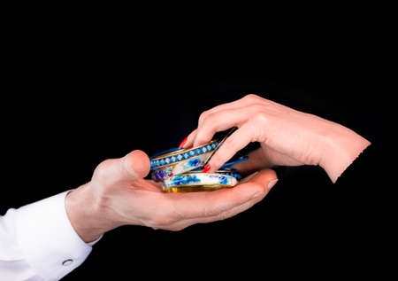Men's hand giving blue bracelet to woman's hands in a black backgroundの写真素材