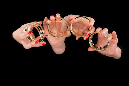 Two women's hands with bracelets  in a black backgroundの写真素材