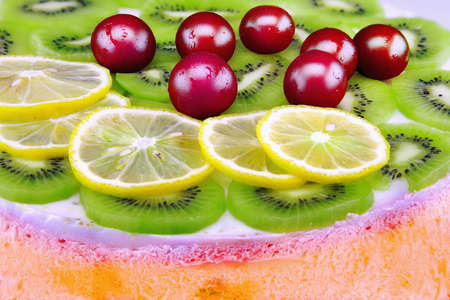Colorful unbaked homemade fruit cake with cream and sweet cherries on a white backgroundの写真素材
