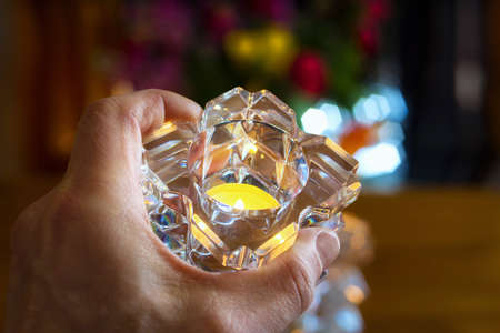 Men's hand with a candle in a colorful blurred backgroundの写真素材