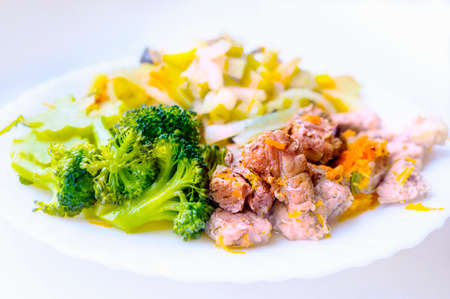 Homemade pork stew with broccoli and other vegetables on a white plate