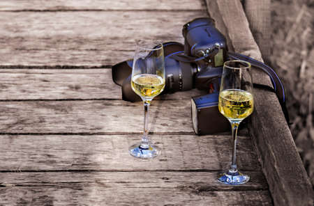 Two glasses of champagne and a photo camera on a wooden backgroundの写真素材