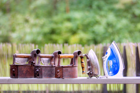 Four vintage rusty irons and one new electric ironの写真素材