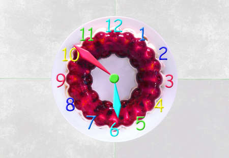 Clock made of a gelly cake showing 6 o'clock with colorful arrowsの写真素材