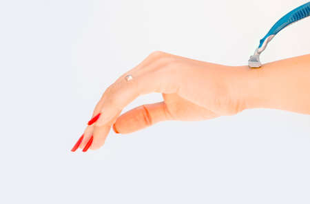 Woman shaving her hand alone with blue shaver on a white backgroundの写真素材