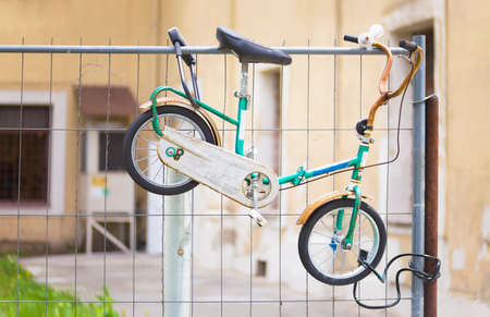 Childs old bicycle chained to a metal fenceの写真素材