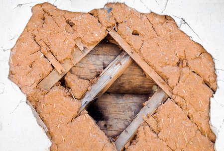 Close view of an old house wall fragment of the old building technology. Logs, laths, clay with...