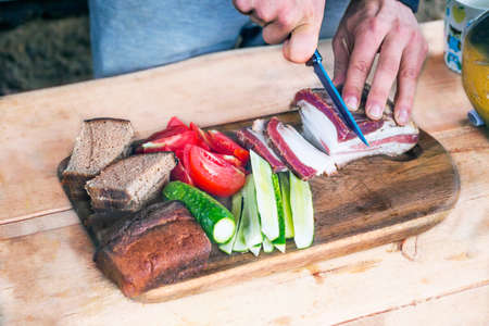 Close view of a man's hand cuts the pieces of fatの写真素材