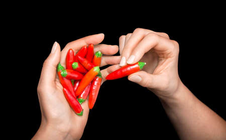 Red hot chili pepper in  woman's hands on a black backgroundの写真素材