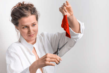 Woman  with old scissors and a small piece of red cloth in a white backgroundの写真素材