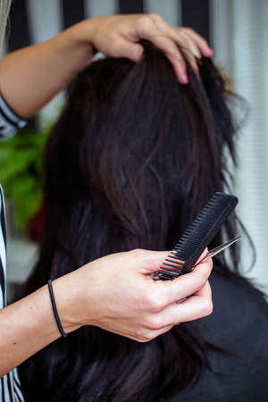 Close view of comb and scissors in the hand of hairdressersの写真素材