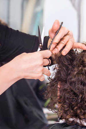 Hairdresser working with  hair in hairdressing salon. Close up view of handsの写真素材