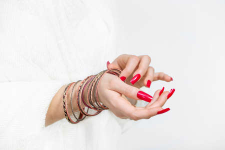Woman's hands with red nails and bracelets on a right hand in a white backgroundの写真素材
