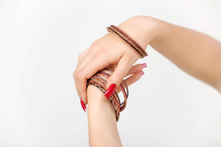 Woman's hands with red nails and bracelets  in a white backgroundの写真素材