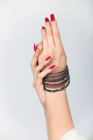 Woman's hands with red nails and bracelets  in a white backgroundの写真素材