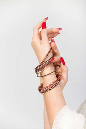 Woman's hands with red nails and bracelets  in a white backgroundの写真素材