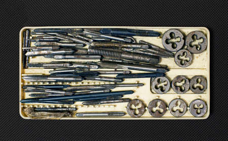 Old rusty locksmith tools - screw taps, in a dusty plastic box