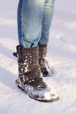 Woman's legs with blue jeans and black shoes in a white snowの写真素材