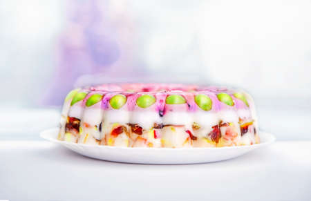 Close view of a colorful jelly cake with a variety of fruits in a  white plateの写真素材