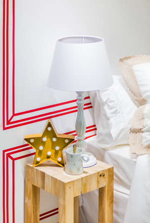 Christmas composition of a star chandelier, mug and a golden spoon on a small table near a bedの写真素材