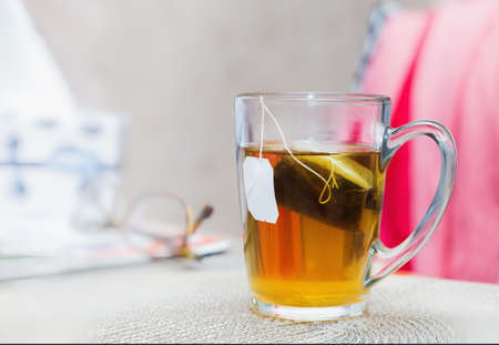 Close view of a glass of  tea with a teabag on a tableの写真素材