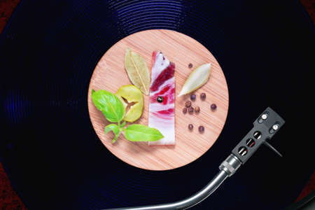 Small round bamboo tray with a piece of bacon, basil, pickled cucumber, bay leaf, a slice of onion...