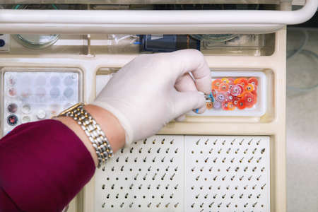 Dentist hand with glove  taking small grinding disk from a drawerの写真素材