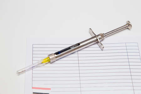 Surgical steel dental syringe with anesthetic cartridge on a white dentist tableの写真素材