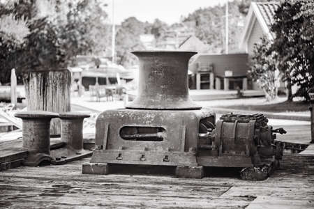 Old vintage metal winch in a port harbour in black white