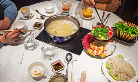 Hands with chopsticks and white dinner table in chinese restaurantの写真素材
